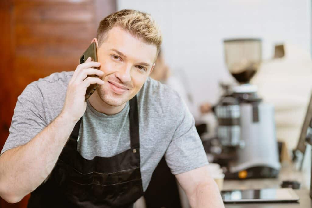 Second Ecommerce Business Model, Maker. Barista male calling talk with customer to receive cafe beverage order by phone happy smile.